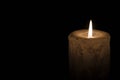 A large candle burns in the dark. On a wooden background. Royalty Free Stock Photo