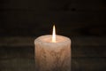 A large candle burns in the dark. On a wooden background. Royalty Free Stock Photo