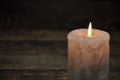 A large candle burns in the dark. On a wooden background. Royalty Free Stock Photo