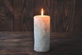A large candle burns in the darkness on a wooden texture background Royalty Free Stock Photo