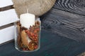 A large candle in a glass vessel. Cones, mountain ash, anise stars, cinnamon sticks are poured into it for decoration. Stands on