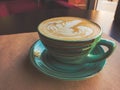 A large cappuccino cup stands on a table covered with Kraft paper. Toning imitates an old film photo