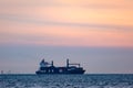 Large cargo ship with cranes carrying a load of shipping containers on the ocean at sunset. Royalty Free Stock Photo