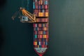 A large cargo ship is docked, with vibrant containers stacked on its deck. A crane is Royalty Free Stock Photo