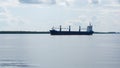 A large cargo ship leaves the port and floats down the river. Freight transport, global communications, transportation