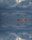 Large cargo ship over the horizon at dusk with reflection Royalty Free Stock Photo