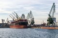 Large cargo ship in the seaport during loading. Cranes load the cargo into the ship. The work of the seaport. Industrial seascape