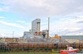 A cement works in with the a boat on the sea in front . Royalty Free Stock Photo