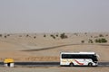 Large charter bus driving down a long, winding road in the Taklamakan Desert Royalty Free Stock Photo