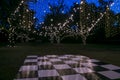 Large checkerboard outdoor dance floor for a party, wedding, event, or reception taken at night with twinkly string