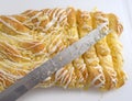 Large cheese danish on a plastic cutting board plus knife Royalty Free Stock Photo