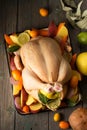 A large chicken stuffed with an apple with vegetables and citrus fruits, top view