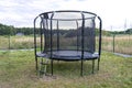 Large childrens jumping trampoline with protective net and closed zipper, standing in the garden.