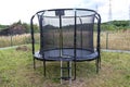 Large childrens jumping trampoline with protective net and closed zipper, standing in the garden.