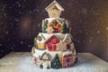 Large Christmas cake decorated with gingerbread cookies and a house on top. Concept of The desserts for the new year