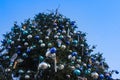 A large Christmas tree decorated with a star and round balls on a blue sky background. Royalty Free Stock Photo