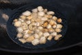 Large chunks of raw lamb fat tail dumba fried in oil with bubbles in a black cauldron close-up