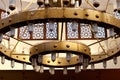 A large circular mosque chandelier ceiling light with lamps and made of copper and other metals fixed to the large mosque masjid