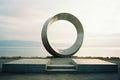 a large circular sculpture in front of a body of water