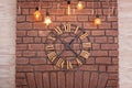 Large classic Clock with roman numerals on a red brick wall. Vintage Clock on wall with glowing garland. Interior concept. Metal w