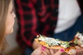 A woman holds a slice of toasted pizza with garlic sauce.