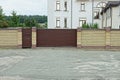 large closed brown gate and door and part of the fence of bricks