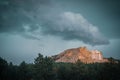 a large cloud is flying over some trees and mountain peaks Royalty Free Stock Photo