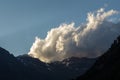 large cloud looming behind a mountain in contrast to the blue sky