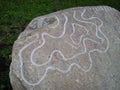 Large cobblestone in the park. Stone-embossed smooth wavy lines. Rock art