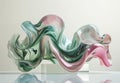 A large, colorful abstract sculpture made of glass in the shape of an ocean wave with pink and green tones