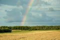 Rainbow on a dark sky over the forest and fields Royalty Free Stock Photo