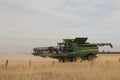 Large machinery harvesting a wheat crop on a farm in an agricultural, dry, windy and dusty farmland area near Melbourne, Royalty Free Stock Photo