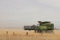 Large machinery harvesting a wheat crop on a farm in an agricultural, dry, windy and dusty farmland area near Melbourne,