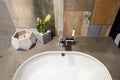 A large comfortable luxurious white sink and faucet in a cozy bathroom with stylish green orange grey blue walls and a flower pot Royalty Free Stock Photo