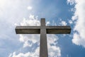 A large concrete cross on a cemetery against a blue sky with white clouds. Royalty Free Stock Photo