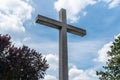 A large concrete cross on a cemetery against a blue sky with white clouds. Royalty Free Stock Photo