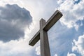 A large concrete cross on a cemetery against a blue sky with white clouds. Royalty Free Stock Photo