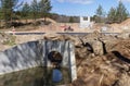 Large concrete new collector for sewer water and heaps of sand with traces of heavy equipment wheels on a construction site