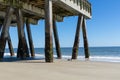 Large concrete pier seen from beneath, blue sky and calm ocean waters, Tybee Island Georgia
