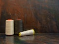 Industrial cones of white and brown sewing threads laying and standing on a dark background. Front view studio shot.
