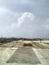 large construction site  Black wire mesh on concrete and sand floors  distant tree buds  The sky above is gray. Royalty Free Stock Photo