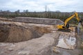 a large construction site, excavators are used to remove topsoil so that a foundation for a large factory building can be built