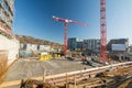 Large construction site with finished foundation, cranes and building material