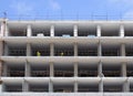 A large construction site of residential apartments with white concrete floors and workers in protective clothing with blue sky