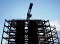 Large construction site in silhouette in the evening with steel girders and a crane in silhouette against a blue cloudy sky Royalty Free Stock Photo