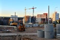 Large construction site with working cranes and heavy machinery for road works, wheel loader, bulldozer, excavator. Royalty Free Stock Photo