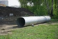 A large corrugated metal pipe with a coupler, prepared for installation, lies on a construction site next to a pile of gravel.