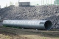 Large corrugated pipe with a coupler, prepared for installation, lies on a construction site next to a pile of gravel. Production