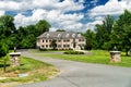 Large country house and summer landscape with perfect lawn. Blue sky and white clouds