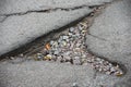 A large crack in asphalt covered with gravel